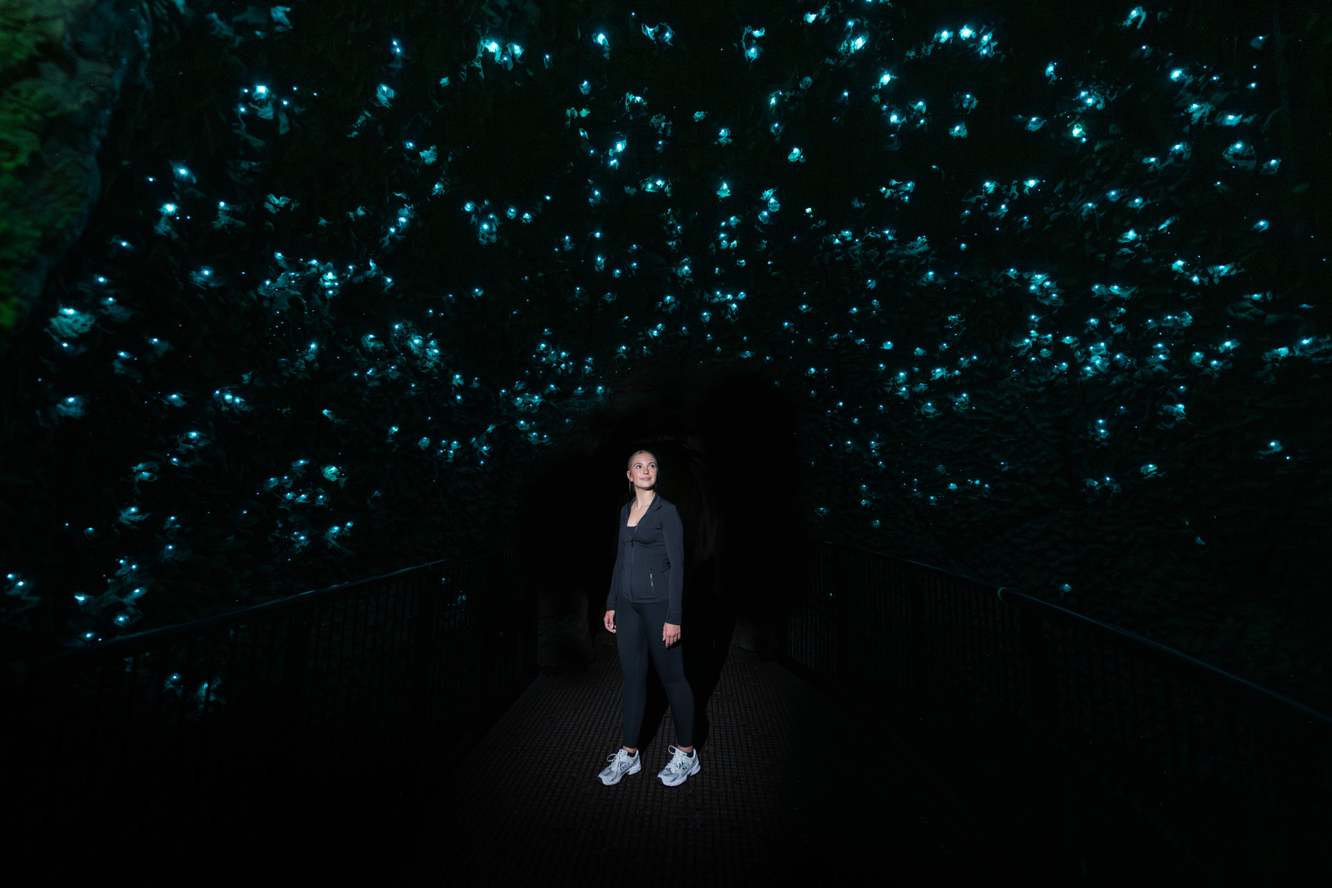 Visitor standing on the walkway beneath a glowworm canopy